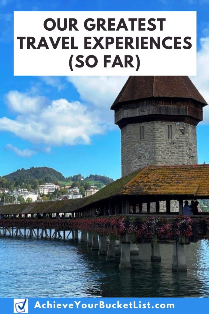A Pinterest image showing the Chapel Bridge in Lucerne Switzerland with baskets of pink flowers hanging off the sides of the bridge. The words on this image say "Our Greatest Travel Experiences (So Far)" and I hope people will pin this blog post to Pinterest.