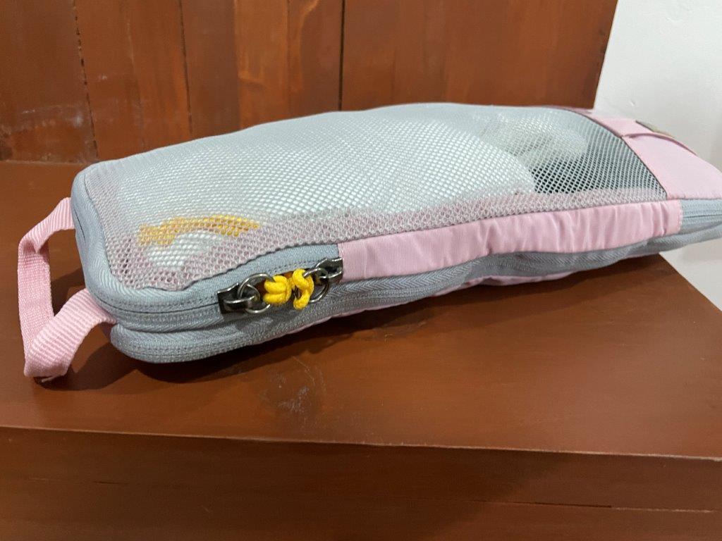 pink and gray packing cube is compressed to take up less room in the suitcase.