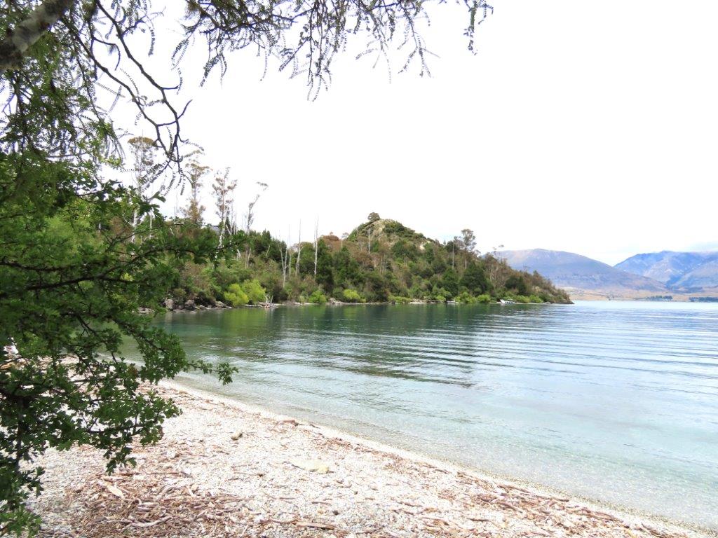 Rocky beach and calm water at Bob’s Cove on Lake Wakatipu near Queenstown. Bob’s Cove is one of the prettiest short hikes in Queenstown for an easy nature walk.