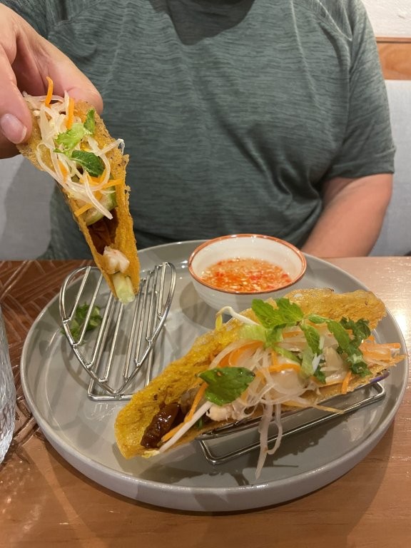 Two hard shelled beef taco, loaded with onions and lettuce and cheese sprinkled on top.