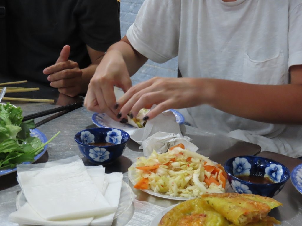 Food tour participant works with the ingredients in front of her to create her own Bahn Xeo.