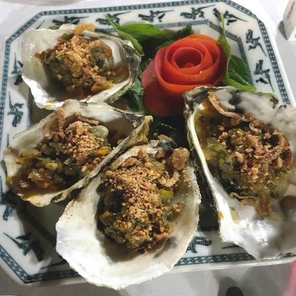 Grilled Oyster meat arranged on 4 Oyster Shells with a decorative rose made from tomatoes.