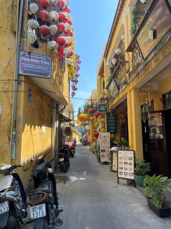 Lanterns adorn this narrow alleyway that has lots of restaurants showing their menu signs. 