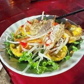A white plate on a red table features cut up vegetables, lettuce and other ingredients.