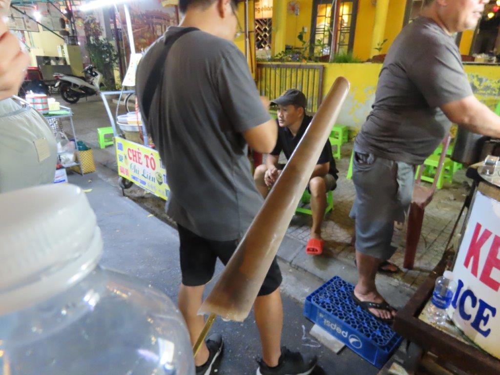 A long slender, light brown shape of frozen ice is an example of Vietnamese ice cream on a stick.