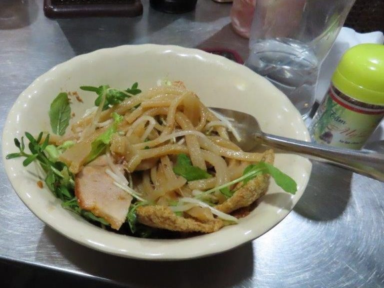 White bowl with noodles, pork and greens - a popular Vietnamese food called Cao Lau.
