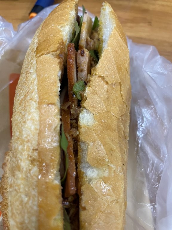 The sandwich features a thick baguette with meat and pate inside of it.