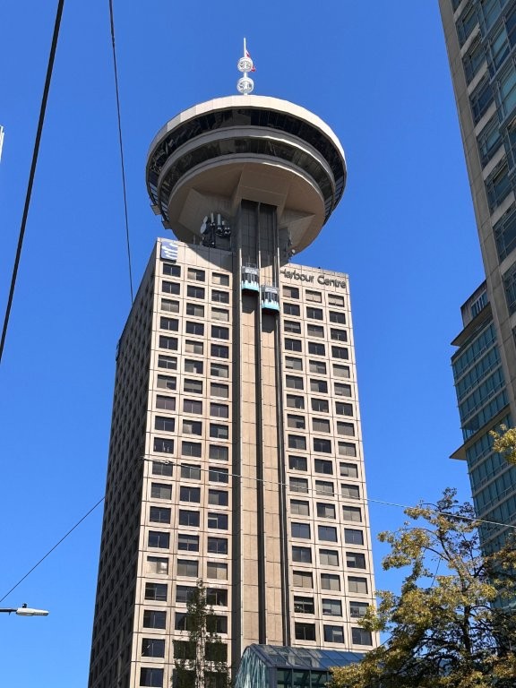 A disc-shaped observation tower perches on top of a 20 story office building. This is the Vancouver Lookout in Downtown Vancouver.