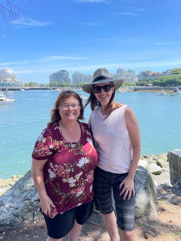 Two women stand in front of the waterway that is False Creek in downtown Vancouver.