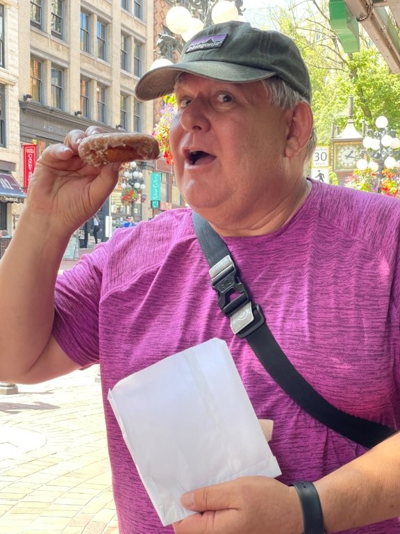 Bill in his pink shirt takes a big bite out of his yummy donut.