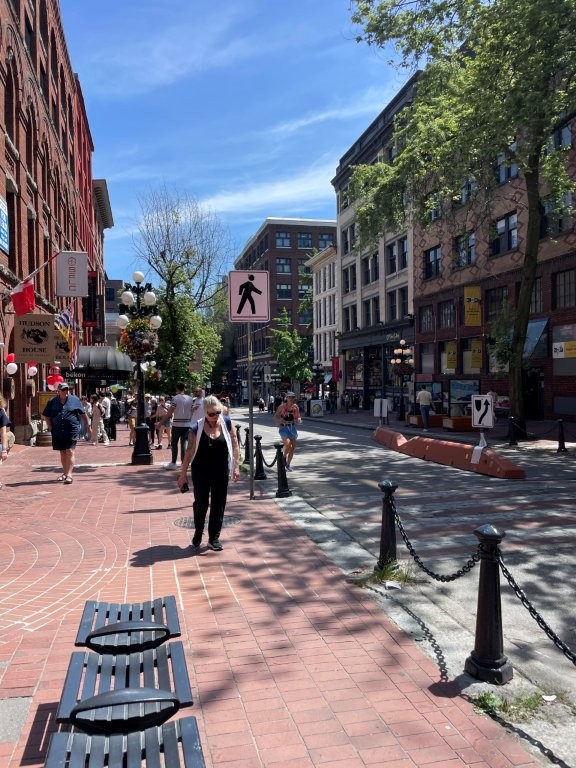 People walk along cobblestone sidewalks in a Pedestrian zone called Gastown - it's a popular stop on a Vancouver Itinerary. 