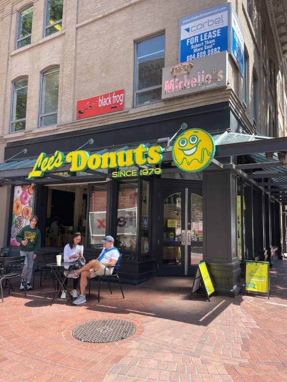 A corner business called Lee's Donuts features bright yellow and green signage, inviting patrons to come in for a taste.