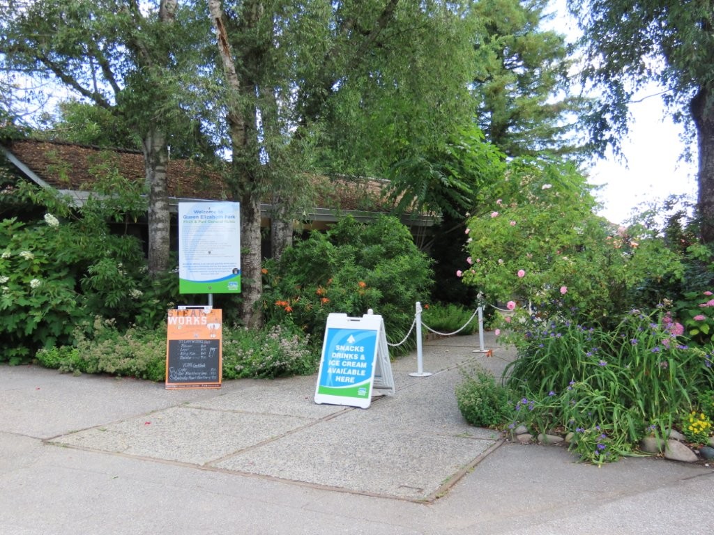 A sidewalk leaves the area with several blue and green signs in front of it.