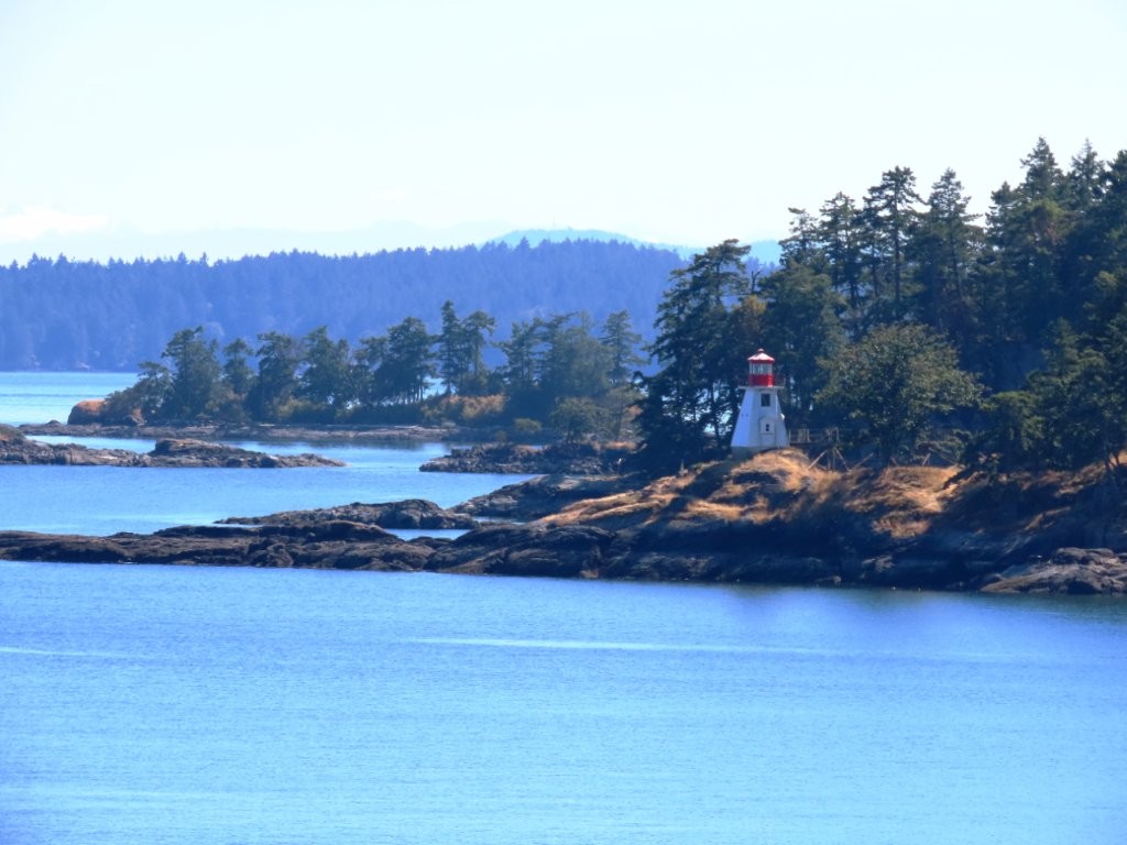Gulf Islands landscape and red-roof lighthouse viewed from the BC Ferry en route to Vancouver Island.”