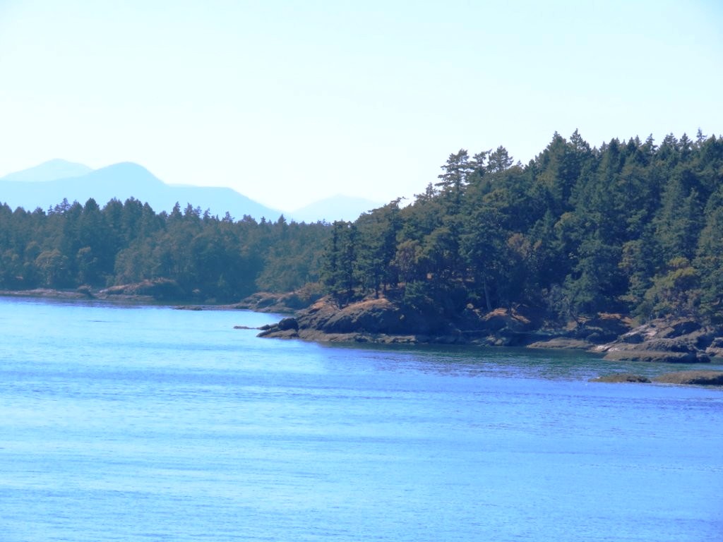 Tree-covered islands and mountain silhouettes captured from a BC Ferry during the crossing to Vancouver Island.