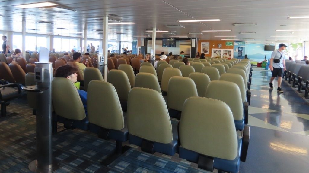 Spacious indoor passenger lounge on BC Ferries with rows of cushioned seats and wide windows.