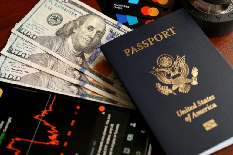 A passport and money are spread across a desk as the owner tries to figure out how to do Costa Rica on a budget.