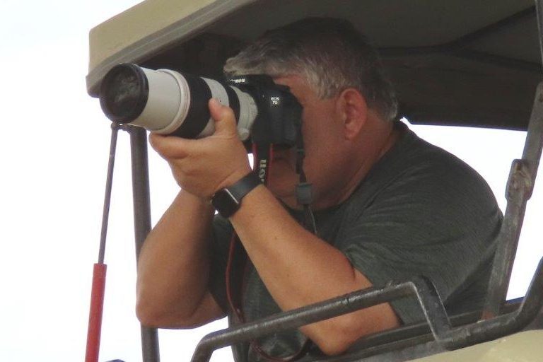 Bill shooting his big camera out of the brown safari vehicle in Africa.