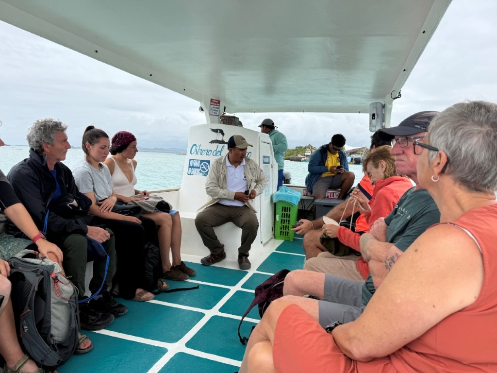 Small group of travelers seated on a boat listening to the naturalist guide during a Las Tintoreras wildlife tour