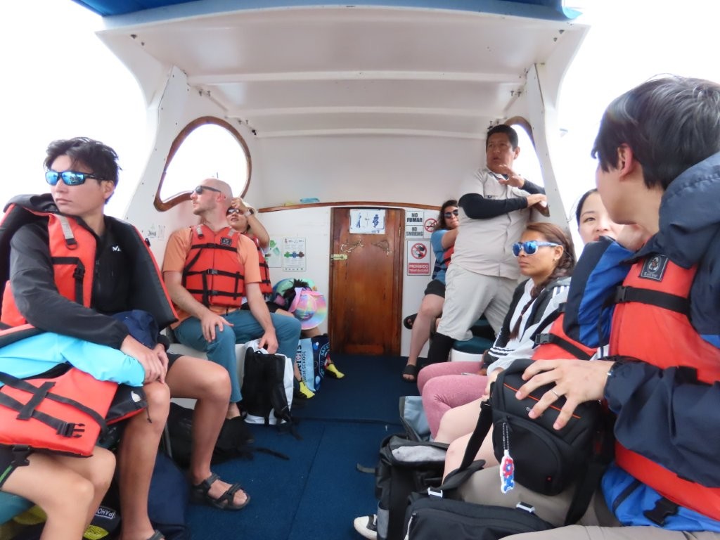 Passengers sit close together inside a small shaded tour boat on the way to Los Túneles. This is where expectations around boat comfort and group size matter before booking a Galapagos day tour.