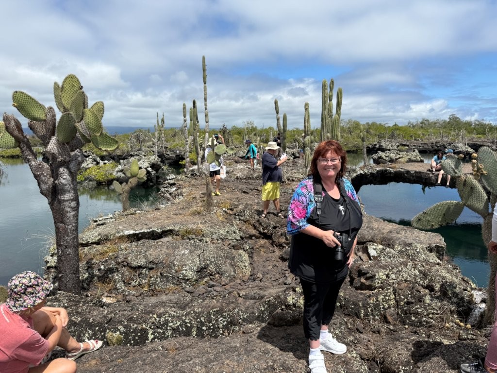 Kari stands on the uneven Lava Rocks with her camera around her neck. 