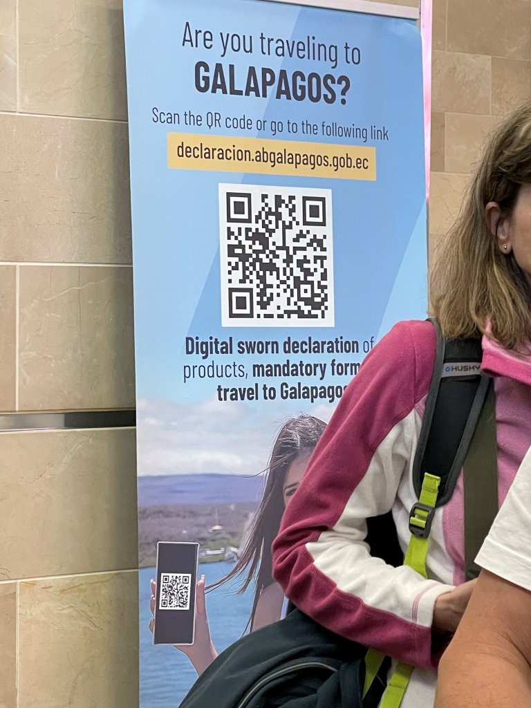 A blue airport sign tells travelers to the Galapagos to scan a QR code for the digital sworn declaration form. Seeing this sign at the airport is exactly why I recommend handling the declaration before travel day.