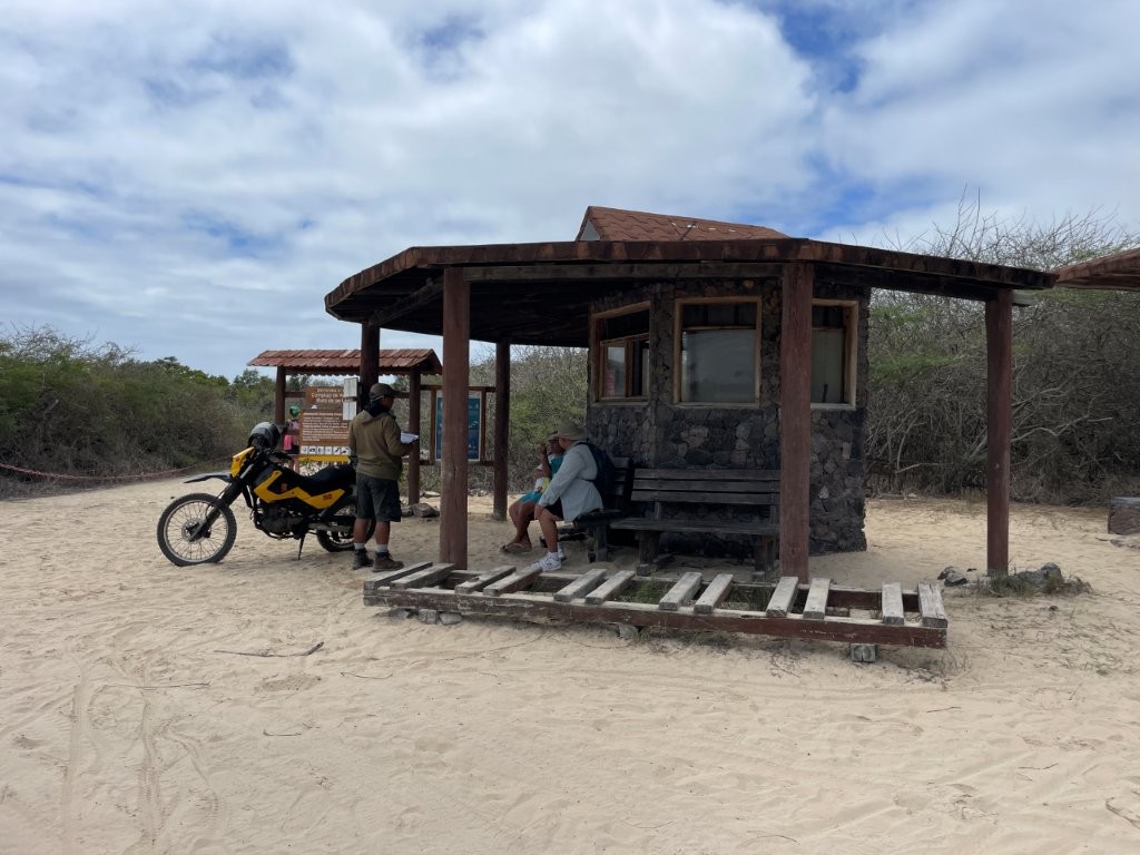 A dark brown building with a wrap around roofline sits in the sand at the start of the Isabela Wetlands. The ranger station is where people check in to enter the park. 
