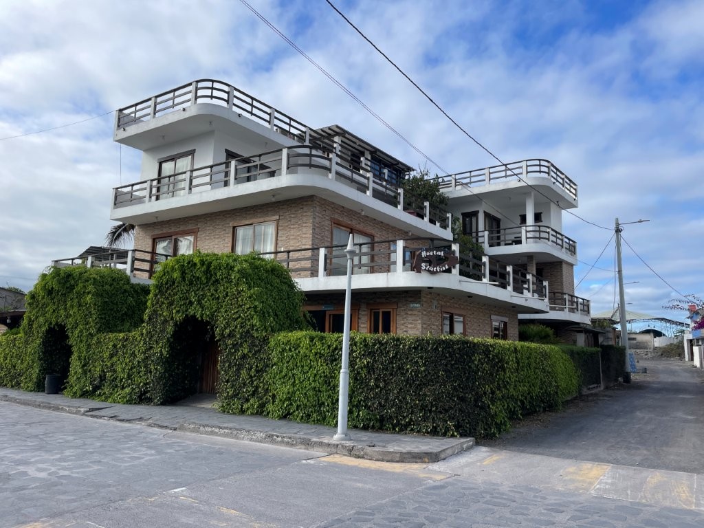 A large corner building with white balconies and green hedges surrounds Hostal Starfish in Puerto Villamil. Hotel StarFish stood out as a practical option for travelers looking for value and convenience on Isabela Island.
