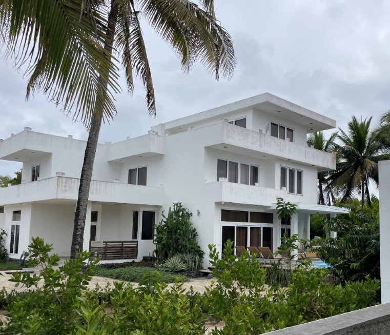 A spacious white villa with multiple terraces rises above tropical plants and palm trees. Yellow Heron House offers more room and privacy than a typical hotel stay on Isabela Island.