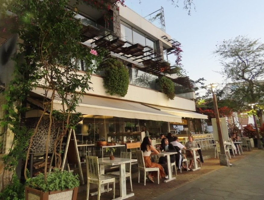 An upscale waterfront restaurant terrace with plants, outdoor seating, and modern architecture overlooks the Malecón at sunset. Golden Bay Galapagos felt noticeably more polished and resort-like than many hotels on San Cristobal Island.