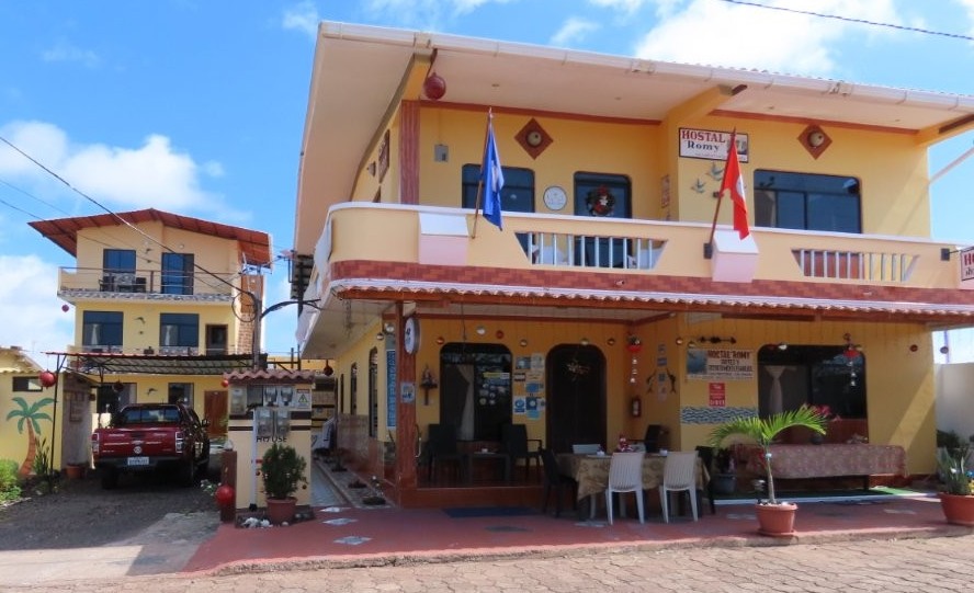 A yellow family-run hostal with covered patios and flags outside sits along a quiet residential street on San Cristobal Island. Hostal Romy stood out as one of the best affordable hotels for travelers wanting a quieter stay near the waterfront.