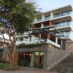 A sleek modern luxury hotel with stone steps and glass balconies rises above the waterfront promenade on San Cristobal Island. Hotel Indigo is one of the most upscale hotel options for travelers researching where to stay in San Cristobal.