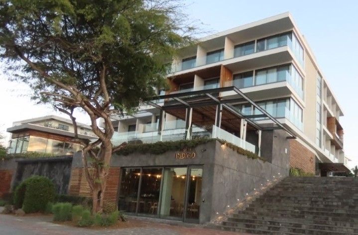 A sleek modern luxury hotel with stone steps and glass balconies rises above the waterfront promenade on San Cristobal Island. Hotel Indigo is one of the most upscale hotel options for travelers researching where to stay in San Cristobal.
