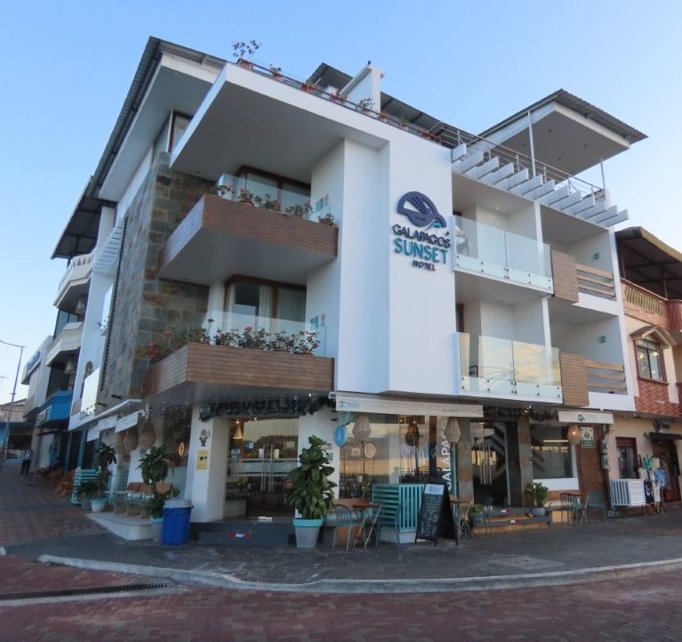 A modern white waterfront hotel with balconies and rooftop terraces stands beside the Malecón on San Cristobal Island. Galapagos Sunset Hotel stood out for its central harbor location and ocean-view rooms.