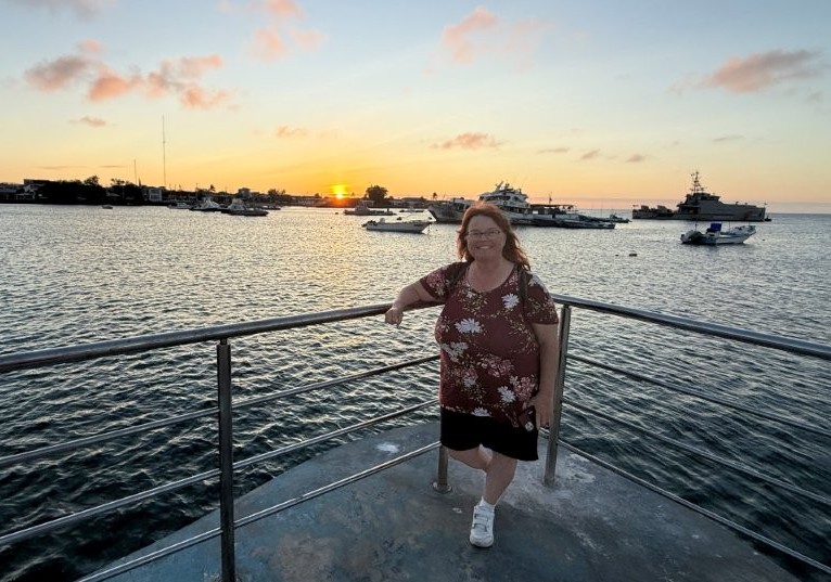 Kari stands at the end of the pier in Puerto Baquerizo Moreno as sunset glows over the harbor and anchored boats. The waterfront sunsets on San Cristóbal became one of my favorite completely free rituals on the island.