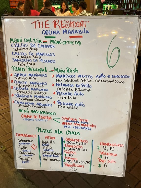 A handwritten restaurant menu board lists seafood soups, ceviche, rice dishes, and budget meal specials along Kiosk Street in Puerto Ayora. Kiosk Street was one of the best budget-friendly food finds we discovered while exploring Santa Cruz Island.