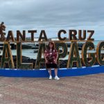 Kari stands smiling in front of the large Santa Cruz Galapagos sign overlooking the waterfront in Puerto Ayora. Visiting the waterfront became one of my favorite free things to do in Santa Cruz Galapagos during our time on the island.