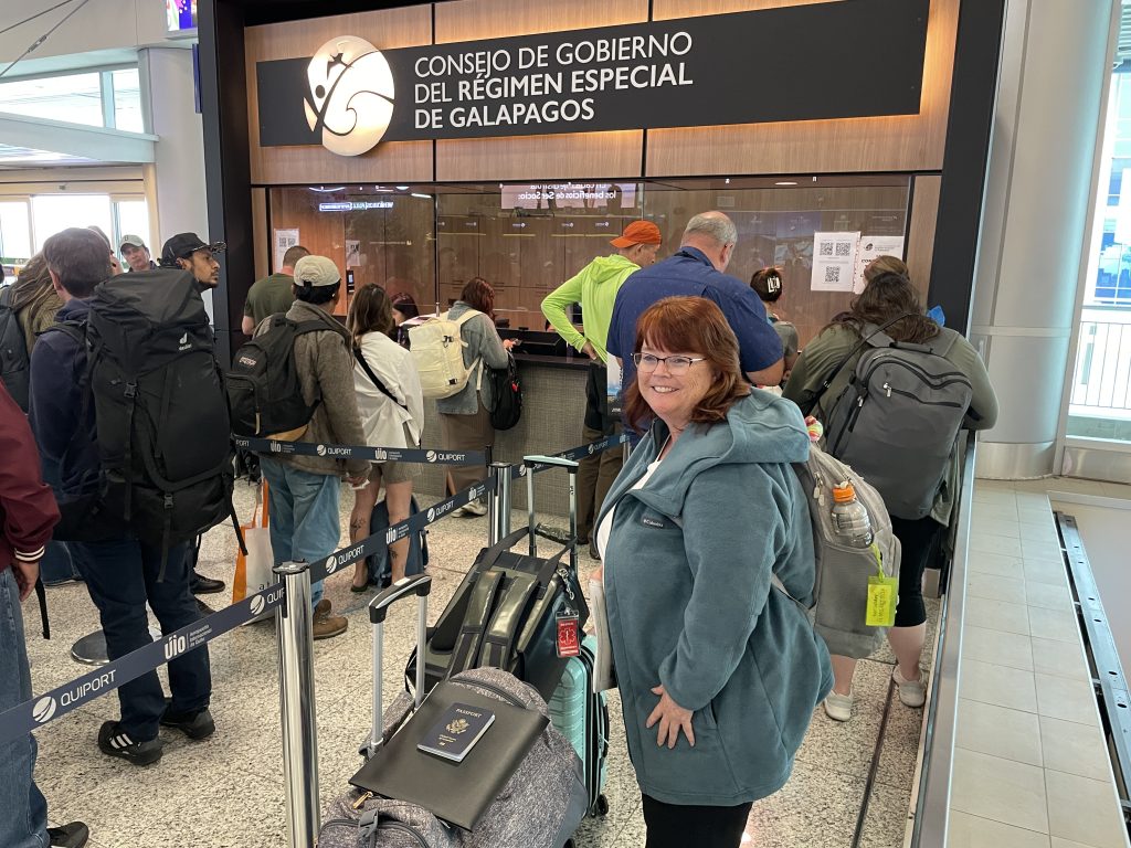 Kari stands beside her luggage in the shorter Galapagos TCT line at the Quito airport. Completing and paying for the TCT online helped make this part of the airport process faster.