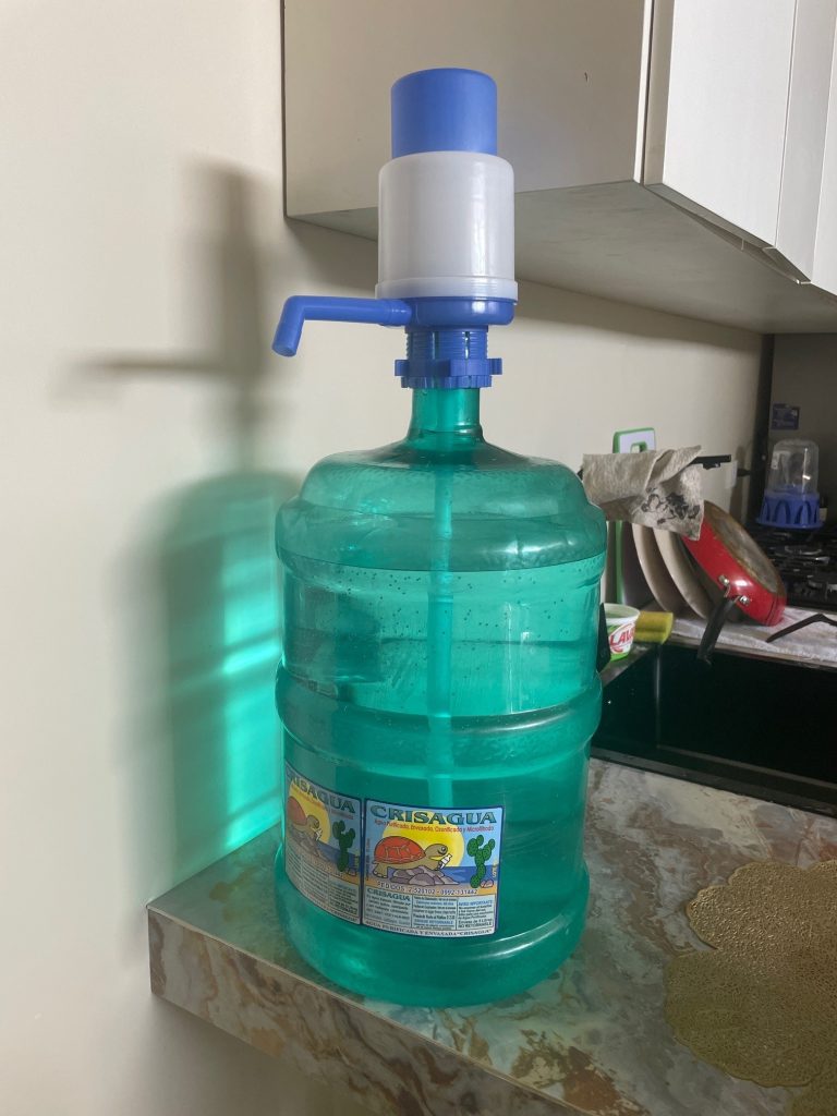 A large green water bottle sits on a counter with a blue and white pump on top. Tap water is not safe to drink in the Galapagos so you must use filtered or bottled water. 