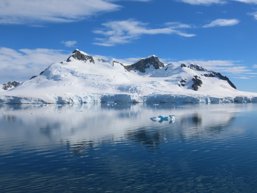 The Antarctic coastline reveals glistening snow-covered mountains.