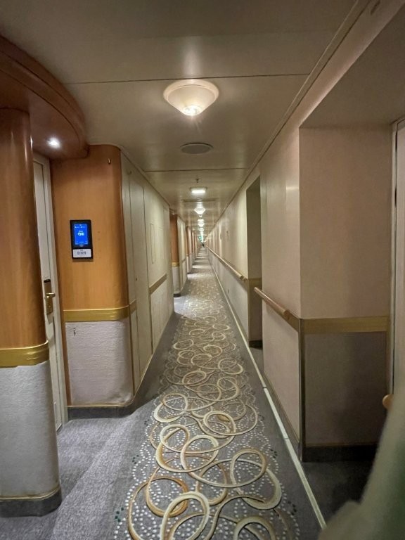 A softly lit long hallway leads to passenger cabins aboard the Sapphire Princess ship.