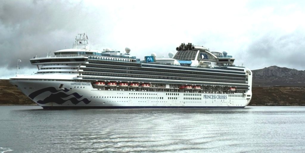 A large cruise ship called Sapphire Princess with many balconies and life boats on it sits in the water. 