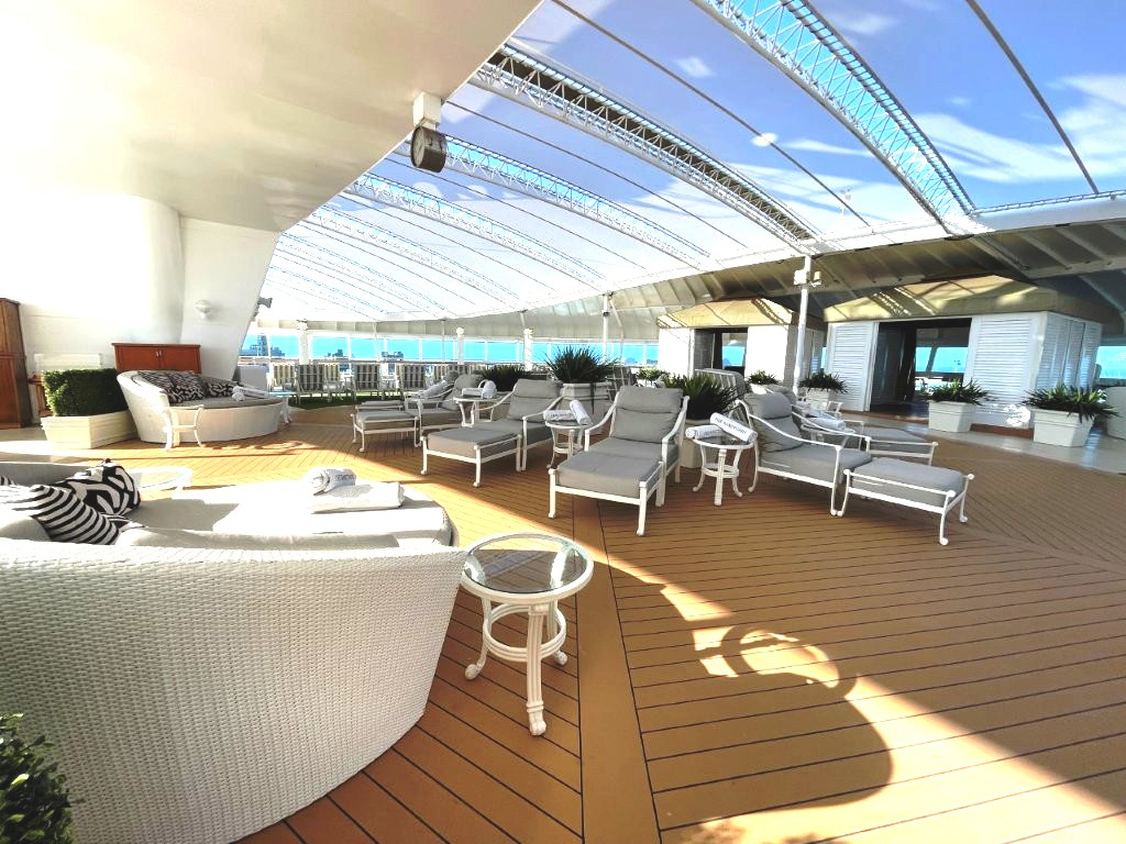 Padded lounge chairs sit beneath fabric canopies overlooking the ocean in The Sanctuary. This adults-only area offers a quieter place to relax away from the main pool deck.