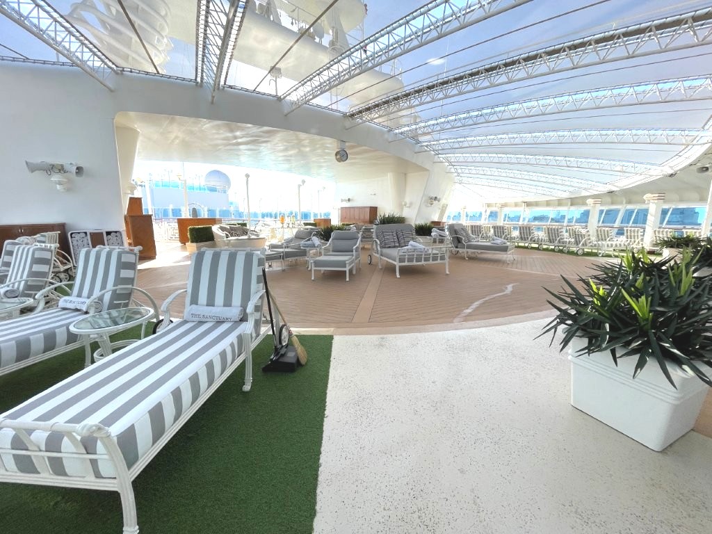 White cushioned loungers face the water inside The Sanctuary with plenty of space between chairs. During our visit it was one of the quietest places anywhere on the ship.