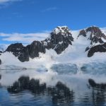 Snow-covered Antarctic mountains and glaciers reflect perfectly in calm blue water beneath a bright summer sky. The best time to visit Antarctica rewarded us with peaceful scenery like this throughout our January cruise.