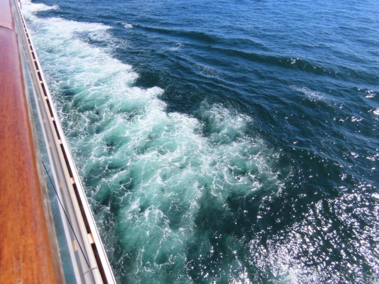 Gentle waves roll past the side of a cruise ship, leaving a ribbon of turquoise wake behind. The photo illustrates the relatively calm conditions we experienced while crossing the Drake Passage.