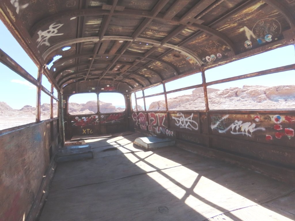 An empty school bus interior shows no windows, no seats, aisle.