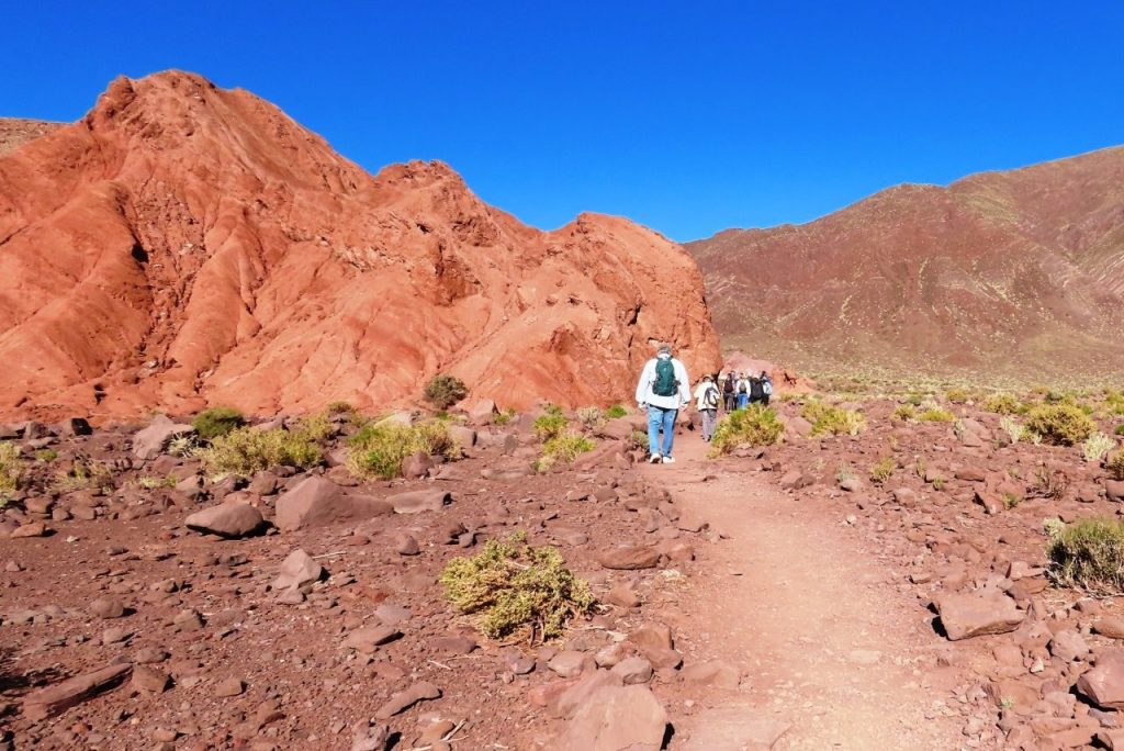Bill walks along the trail in the bright red valley of colorful rocks at Rainbow Valley.