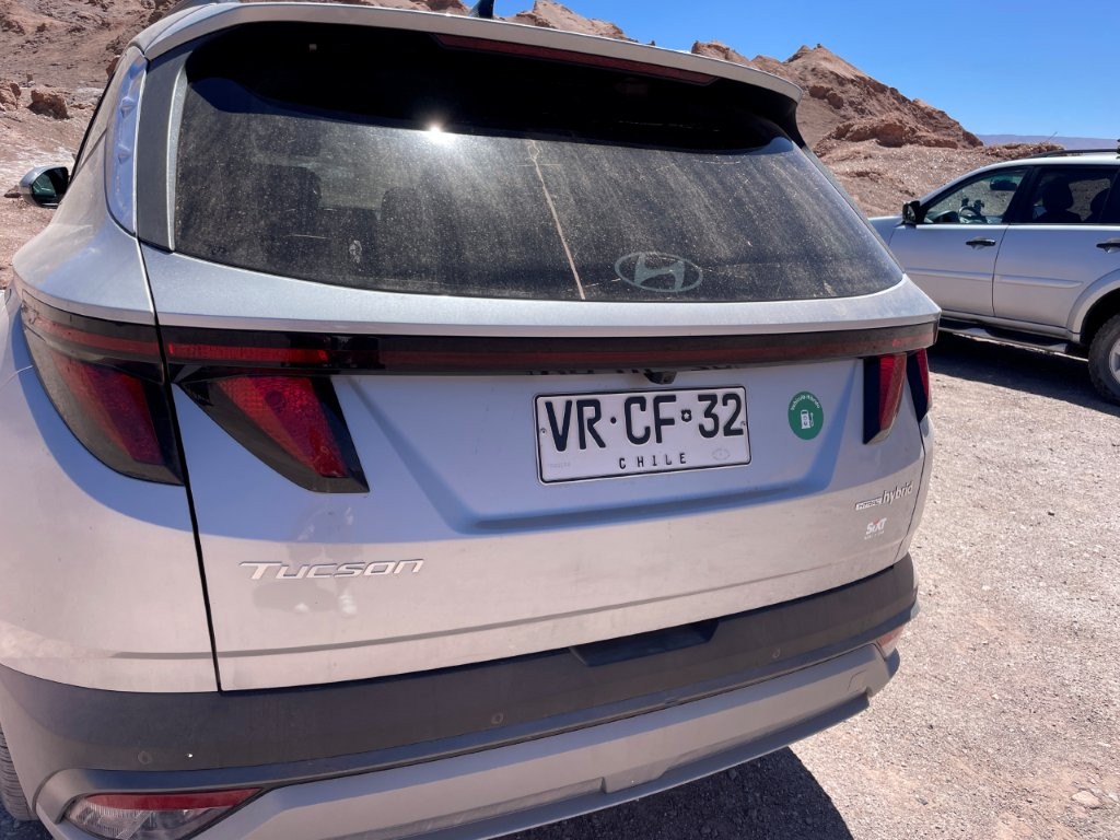 Dust-covered Hyundai Tucson rental car parked at a desert attraction after several days of exploring the Atacama. The layer of dust is a realistic reminder of what to expect when driving the region's dry roads.