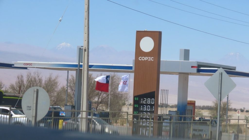 A gas station in San Pedro de Atacama stands against a backdrop of desert plains and distant volcanoes. Fueling up before heading into the remote Atacama landscape is an important part of any road trip itinerary.